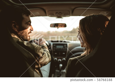 Young couple sitting on front passenger seats and looking at each other. Young couple sitting on front passenger seats and looking at each other. 58768188