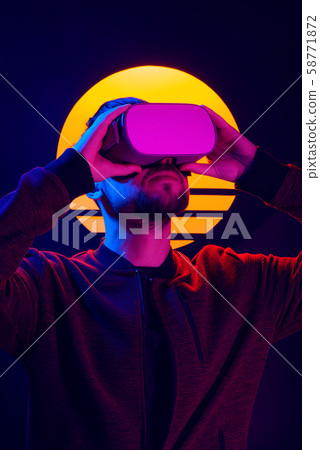 Man wearing virtual reality goggles. VR head set videogame in 80's synthwave and retrowave futuristic aesthetics. 58771872