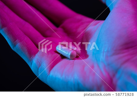 Two pills in hand closeup on dark background. Drugs tablet in palm. 58771928
