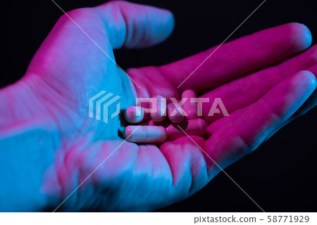 Heap of pills in hand closeup on dark background. Drugs tablets pile in palm. 58771929