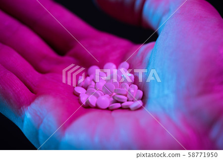 Round white drug pills tablets heap in hand on black background 58771950