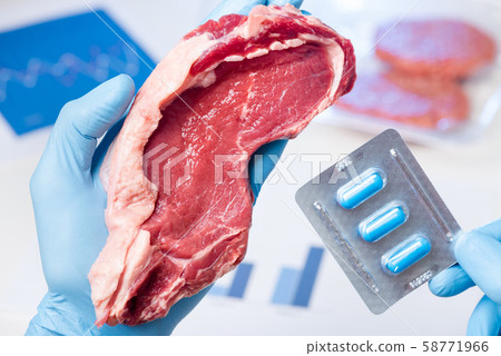 Fresh red meat steak and drugs pills in laboratory scientist hands. Livestock meat antibiotic and hormone use concept. 58771966