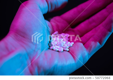 Pills pile in hand. Drug tablets in palm close-up on dark background 58772068