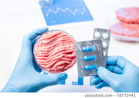 Meat in lab Perti dish and pills blisters in scientist hands. Antibiotic use in livestock research concept. Meat in lab Perti dish and pills blisters in scientist hands. Antibiotic use in livestock research concept. 58772441