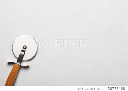 Clean new pizza cutter with wooden handle on stucco table top view with copy-space Clean new pizza cutter with wooden handle on stucco table top view with copy-space 58772468