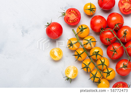 Small cherry tomatoes assortment, fresh red ripe on branch, red and yellow, whole and cut in half, on rustic table flat lay with copy space. Small cherry tomatoes assortment, fresh red ripe on branch, red and yellow, whole and cut in half, on rustic table flat lay with copy space. 58772473