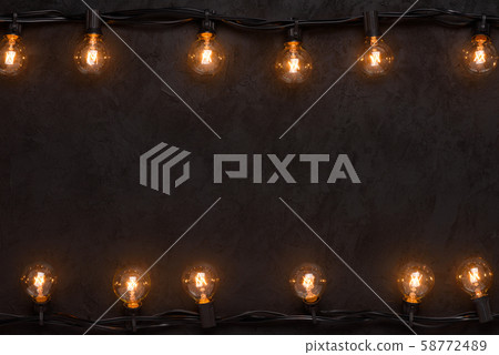 Light bulbs retro garland on dark black wall background Light bulbs retro garland on dark black wall background 58772489