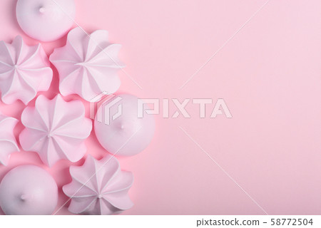 Meringue cookies. Sweet crispy twisted and drop meringue on pink pastel background with copy-space. Meringue cookies. Sweet crispy twisted and drop meringue on pink pastel background with copy-space. 58772504