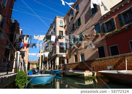 Venice Italy street with laundry washed clothes hanging out to dry on ropes between houses over the canal Venice Italy street with laundry washed clothes hanging out to dry on ropes between houses over the canal 58772524
