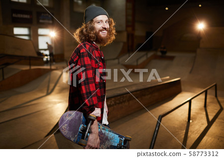 Smiling Young Man Holding Skateboard 58773312