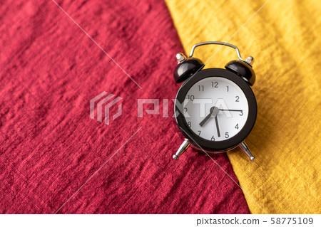 The black clock place on the red and yellow fabric 58775109