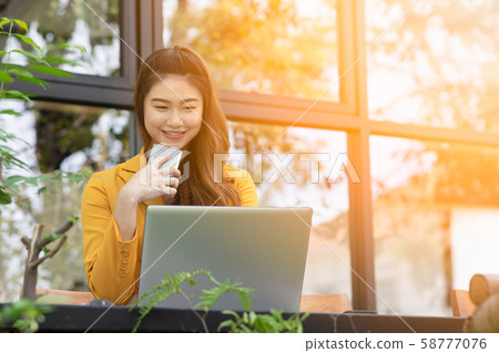 Beautiful Young Asian Woman smile and using Smartphone to connecting social media or Shopping online from App in device at coffee shop cafe enjoy and happiness,Woman with Smartphone Concept 58777076