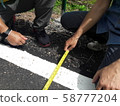 Technician measuring the width of the road 58777204