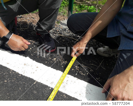 Technician measuring the width of the road 58777204
