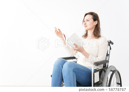 Foreign woman reading in wheelchair 58778787