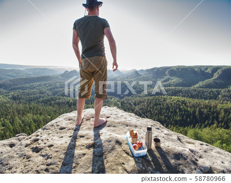 Man with lunch box on cliff at sunset time, sun Man with lunch box on cliff at sunset time, sun 58780966