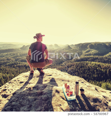 Young man relaxing on rocky cliff. Man sitting on 58780967