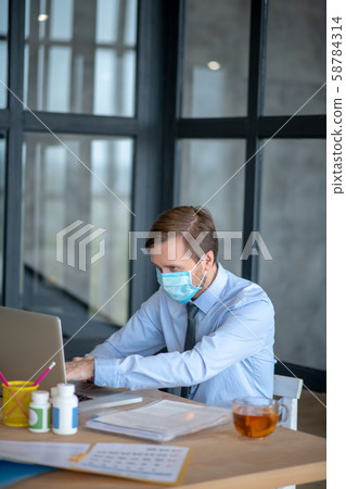 Office worker wearing mask while working in the office Office worker wearing mask while working in the office 58784314