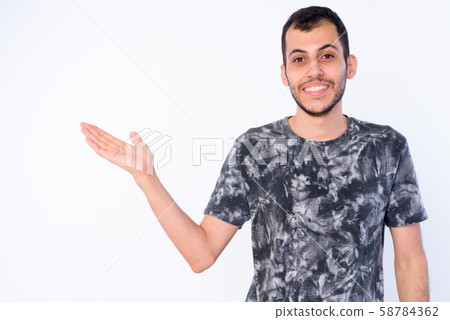 Portrait of happy young bearded Persian man showing something 58784362