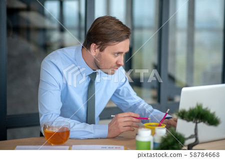Dark-haired interior designer standing near laptop and working 58784668
