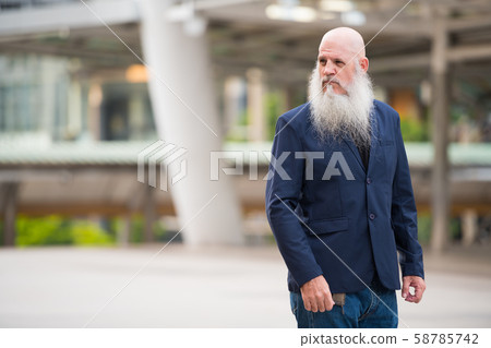 Mature bearded bald businessman thinking in the city outdoors Mature bearded bald businessman thinking in the city outdoors 58785742