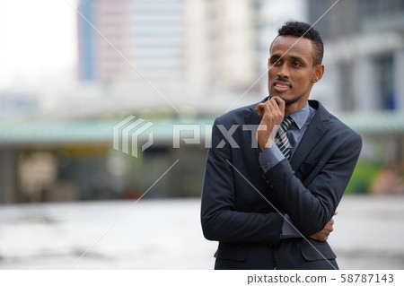 Happy young African businessman thinking in the city streets outdoors 58787143