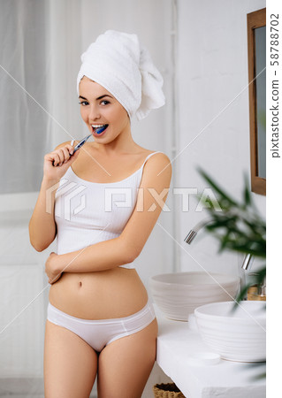 Beautiful young woman brushing teeth Beautiful young woman brushing teeth 58788702
