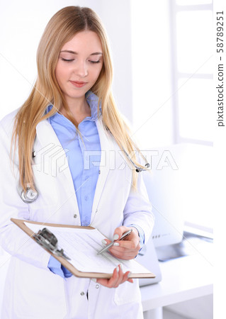 Young woman doctor at work in hospital office. Blue color blouse of therapist looks good. Medicine 58789251