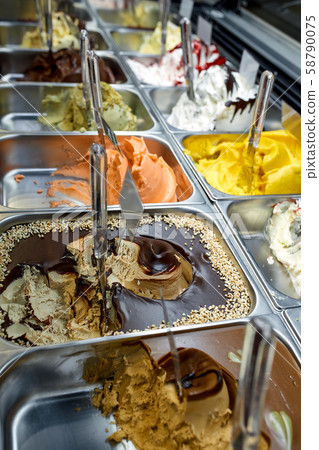 Ice cream showcase with lots of different sorts of ice cream. 58790075