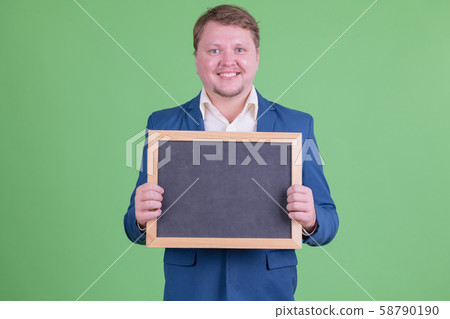 Portrait of happy overweight bearded businessman holding blackboard 58790190