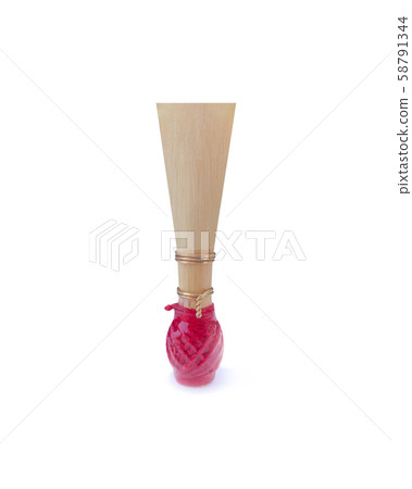 Double reed for bassoon with red thread on a white background. Tongue mouthpiece for wind musical instruments. With a slight shadow. 58791344