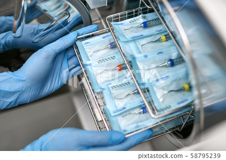 Dentist is loading dental probes into sterilize machine Dentist is loading dental probes into sterilize machine 58795239