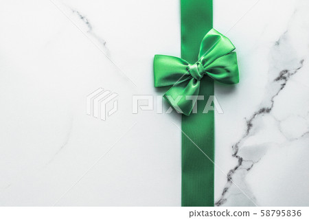 Green silk ribbon and bow on marble background, St Green silk ribbon and bow on marble background, St 58795836