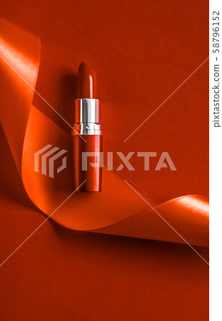 Luxury lipstick and silk ribbon on orange holiday Luxury lipstick and silk ribbon on orange holiday 58796152