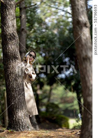 Beautiful woman with a headscarf in a trench coat playing a spy 58796693