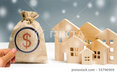 Money bag and a wooden houses with snow. 58796909