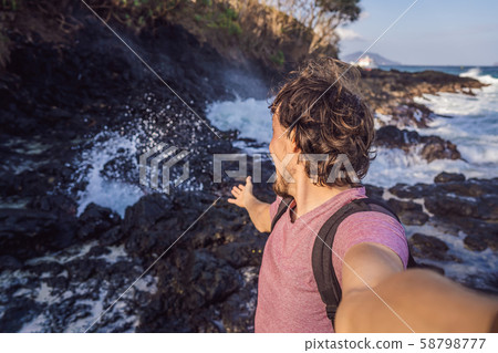 Smiling guy in the sea spray on the rocks Smiling guy in the sea spray on the rocks 58798777