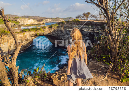 Young woman tourist near Broken Beach in Nusa Penida, Indonesia Angel's BillaBong Beach. Popular Young woman tourist near Broken Beach in Nusa Penida, Indonesia Angel's BillaBong Beach. Popular 58798858