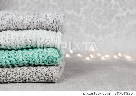 Stylish knitted pastel colored sweaters folded in stack on velvety fabric background. Winter and Stylish knitted pastel colored sweaters folded in stack on velvety fabric background. Winter and 58798859