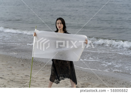 A female copy space that stands on the beach with a strong white cloth that challenges the battle. 58800882