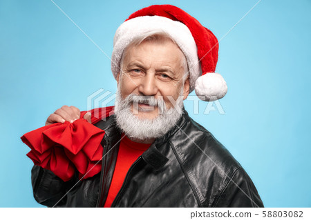 Portrait of man in Santa hat posing in studio with red sack 58803082