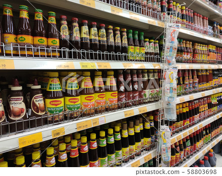 Selective focused variety of cooking sauce in the bottles displayed for sale in the supermarkets. Displayed on racks and separated by the brand to facilitate buyers. 58803698