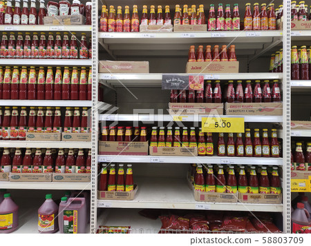 Selective focused variety of cooking sauce in the bottles displayed for sale in the supermarkets. Displayed on racks and separated by the brand to facilitate buyers. 58803709