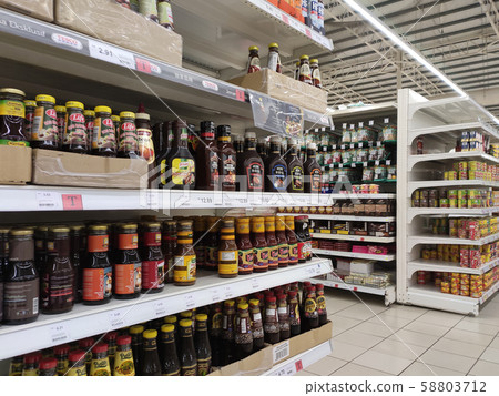 Selective focused variety of cooking sauce in the bottles displayed for sale in the supermarkets. Displayed on racks and separated by the brand to facilitate buyers. 58803712