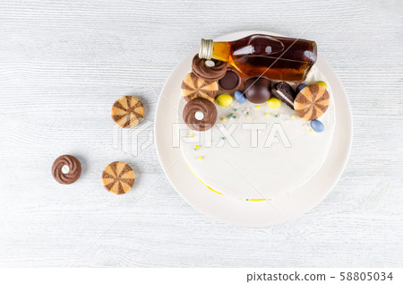 funny cake with a bottle of alcohol, candy and cookies on wooden table 58805034