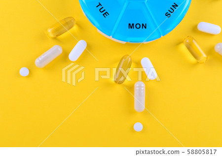 different medicines for one week and a pills box on yellow background with copy space different medicines for one week and a pills box on yellow background with copy space 58805817