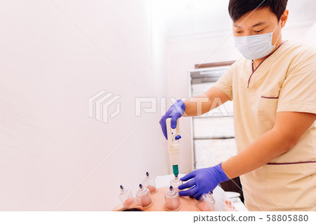 Therapist giving cupping therapy- Hijama to woman 58805880