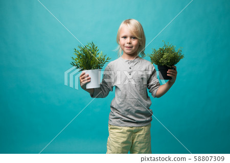 A little boy holding pots with a green plant. Children and nature. Preserve nature A little boy holding pots with a green plant. Children and nature. Preserve nature 58807309