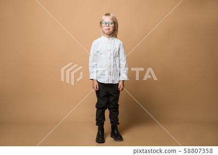 A boy in glasses dressed in white shirt, black trousers thinks about serious plans. School 58807358