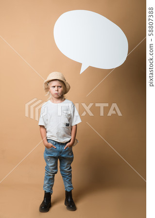 A boy in a hat stands on an orange background and shows emotions 58807388